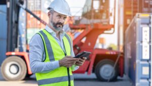 CEO or Manager in white helmet with tablet control loading Conta